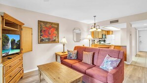 A living room with a sofa, coffee table, TV, and wooden furniture.