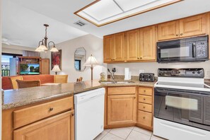 Une cuisine moderne avec des meubles en bois, un four à micro-ondes, une cuisinière et un lave-vaisselle.