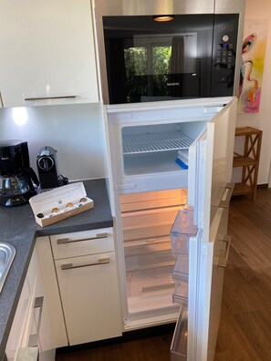 Une cuisine moderne équipée d’un réfrigérateur encastré, d’une machine à café et d’un four à micro-ondes.