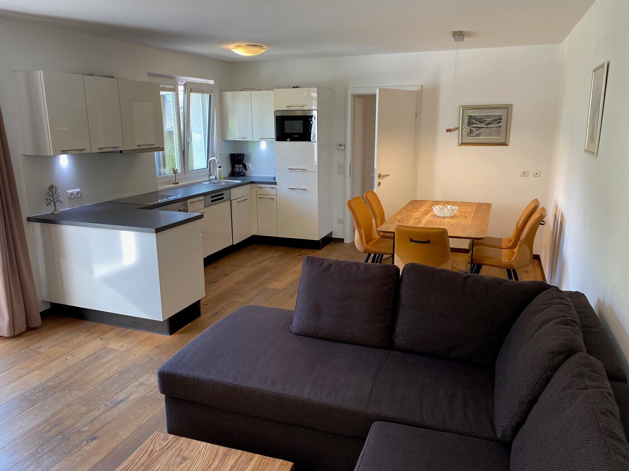 A compact living space with a kitchenette, a dining area with a table and chairs, and a sofa.