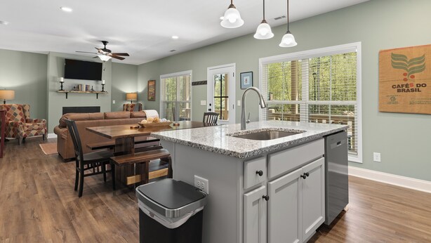 A modern kitchen with a granite countertop, white cabinets, and a built-in dishwasher. - Babbling Brook-New construction (Maggie Valley)