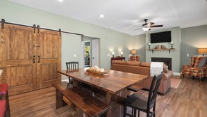 A spacious living room with a wooden dining table, a sofa, and a fireplace. - Babbling Brook-New construction (Maggie Valley)