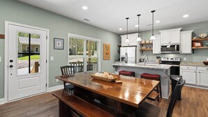 A modern kitchen with a wooden island, white cabinets, and a stainless steel refrigerator. - Babbling Brook-New construction (Maggie Valley)