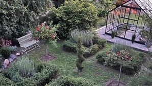 A well-maintained garden with a metal bench, various shrubs, and a greenhouse structure. - Apartment LA BASTIDE (Rosières, Haute-Loire)