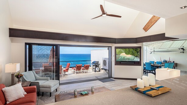 A modern living room with a large sliding glass door leading to a balcony with a view of the ocean. - Puu Poa 407: 2  BR, 2  BA Condominium in Princeville, Sleeps 4 (Princeville)