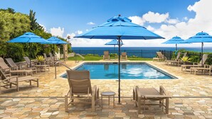 A pool area with lounge chairs and umbrellas, a stone-tiled deck, and a view of the ocean. - Puu Poa 407: 2  BR, 2  BA Condominium in Princeville, Sleeps 4 (Princeville)