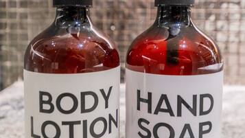 Two bottles of body lotion and hand soap on a marble countertop.
