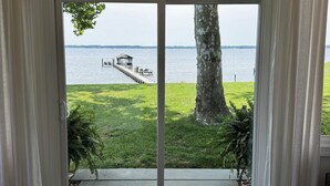 A room with a large sliding glass door leading to a deck overlooking a lake.