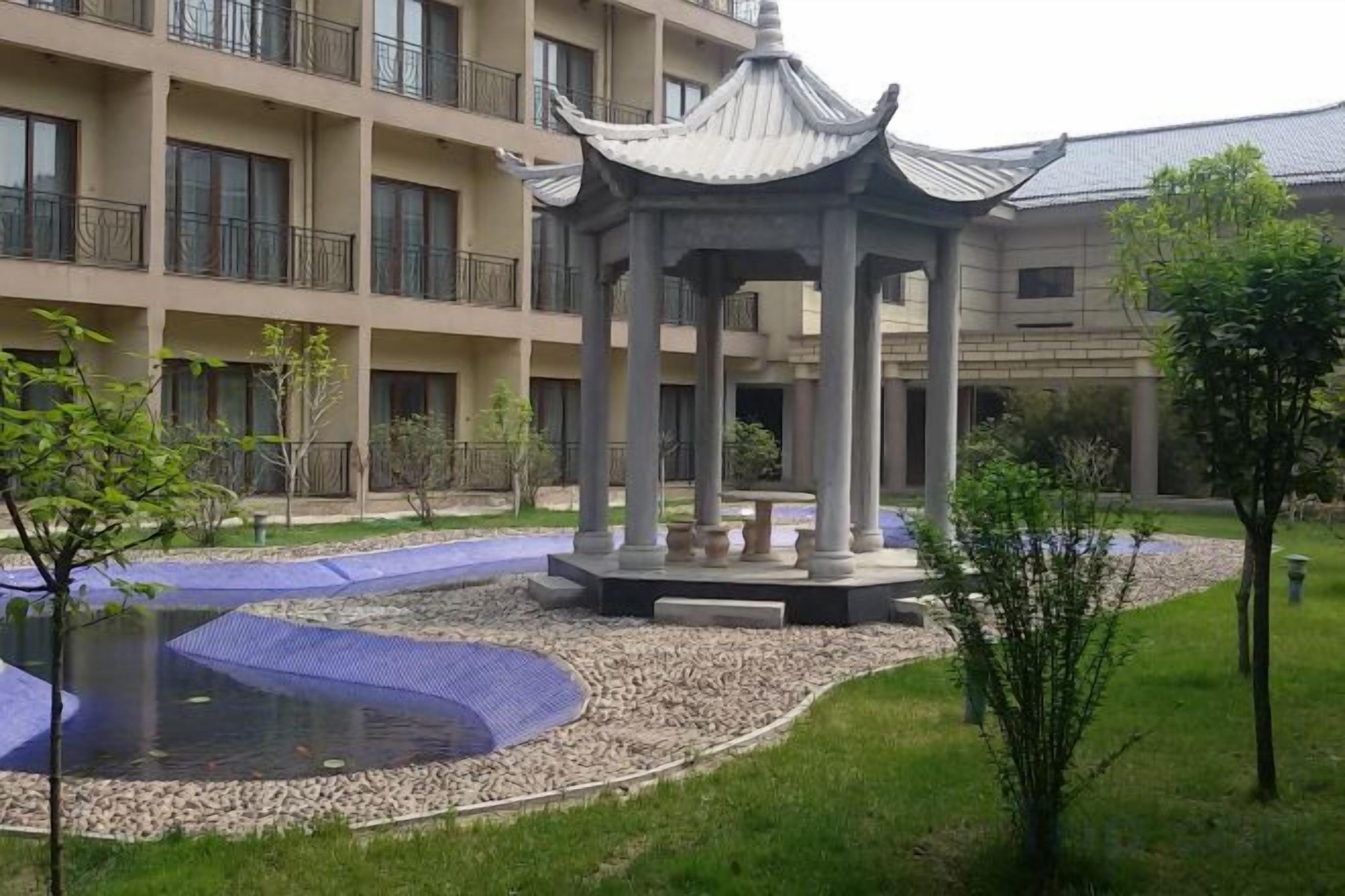 A courtyard with a traditional pavilion, a swimming pool, and a multi-story building with balconies.