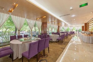 A restaurant with round tables, purple chairs, and a view of parked cars outside. - Huanghe Guesthouse (Kaifeng)