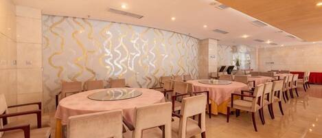 A hotel dining area with round tables, chairs, and a modern interior design.