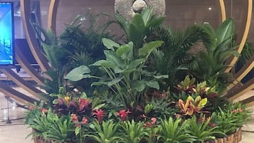 A circular wooden planter with various green plants and red flowers.