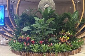 A circular wooden planter with various green plants and red flowers. - Huanghe Guesthouse (Kaifeng)