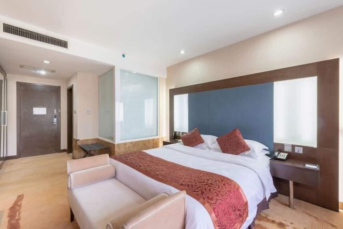 A hotel room with a large bed, a desk, and a seating area.