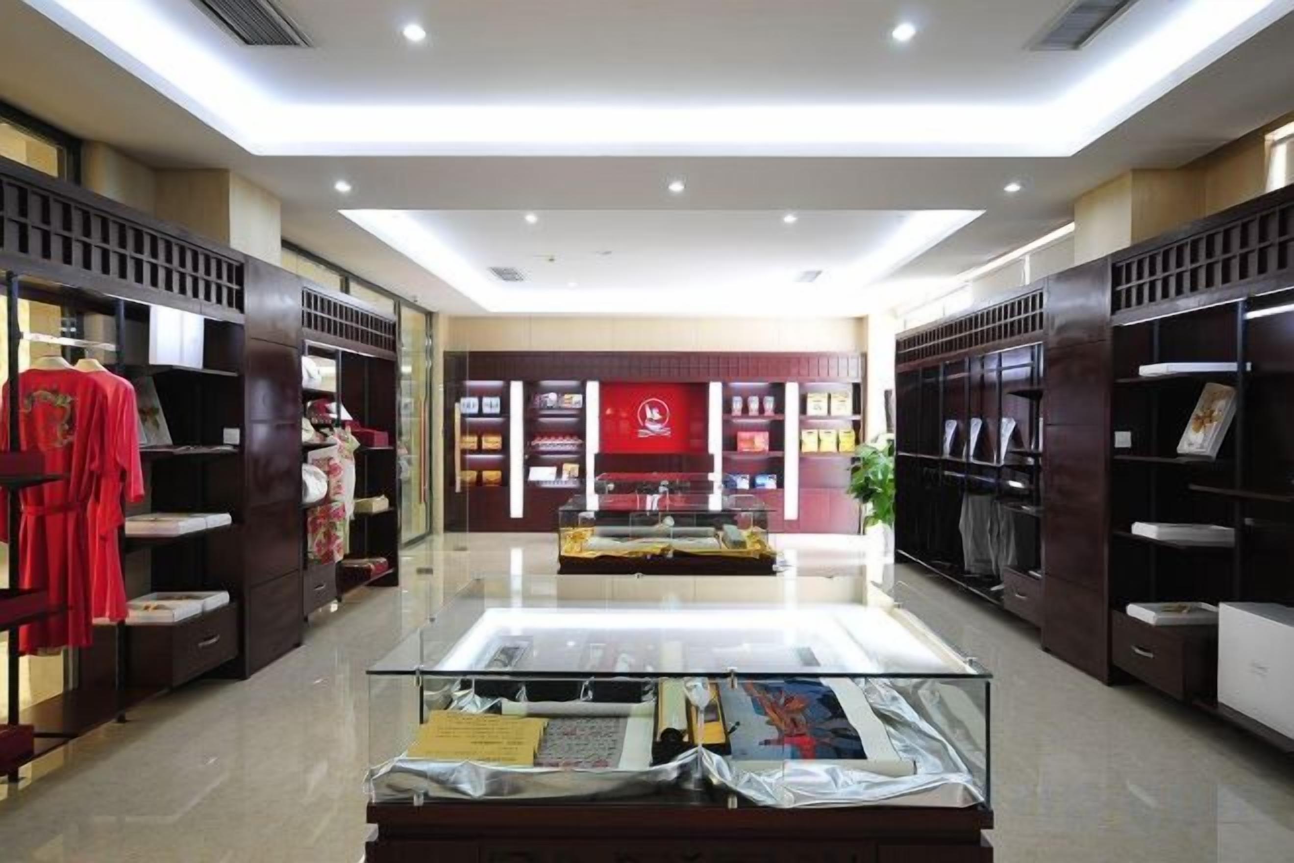 A hotel lobby with a central display case, shelves with items, and a red wall with information.