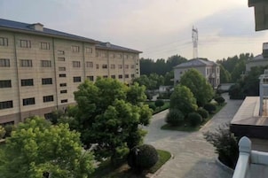 A multi-story building with a central courtyard, surrounded by trees and a clear sky.