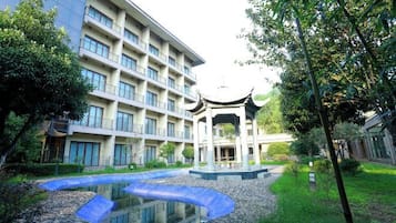 A courtyard with a traditional pavilion, a modern building, and a small pond.