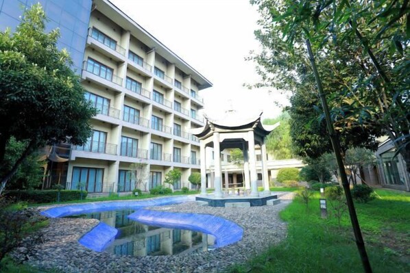 A courtyard with a traditional pavilion, a modern building, and a small pond. - Huanghe Guesthouse (Kaifeng)