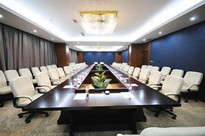 Un salón de conferencias con una larga mesa, sillas y una lámpara de araña.