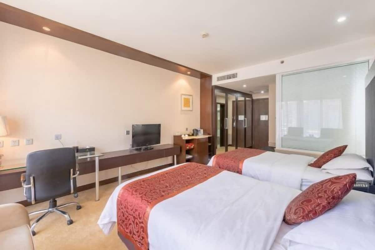 A hotel room with two beds, a desk with a computer, and a TV.