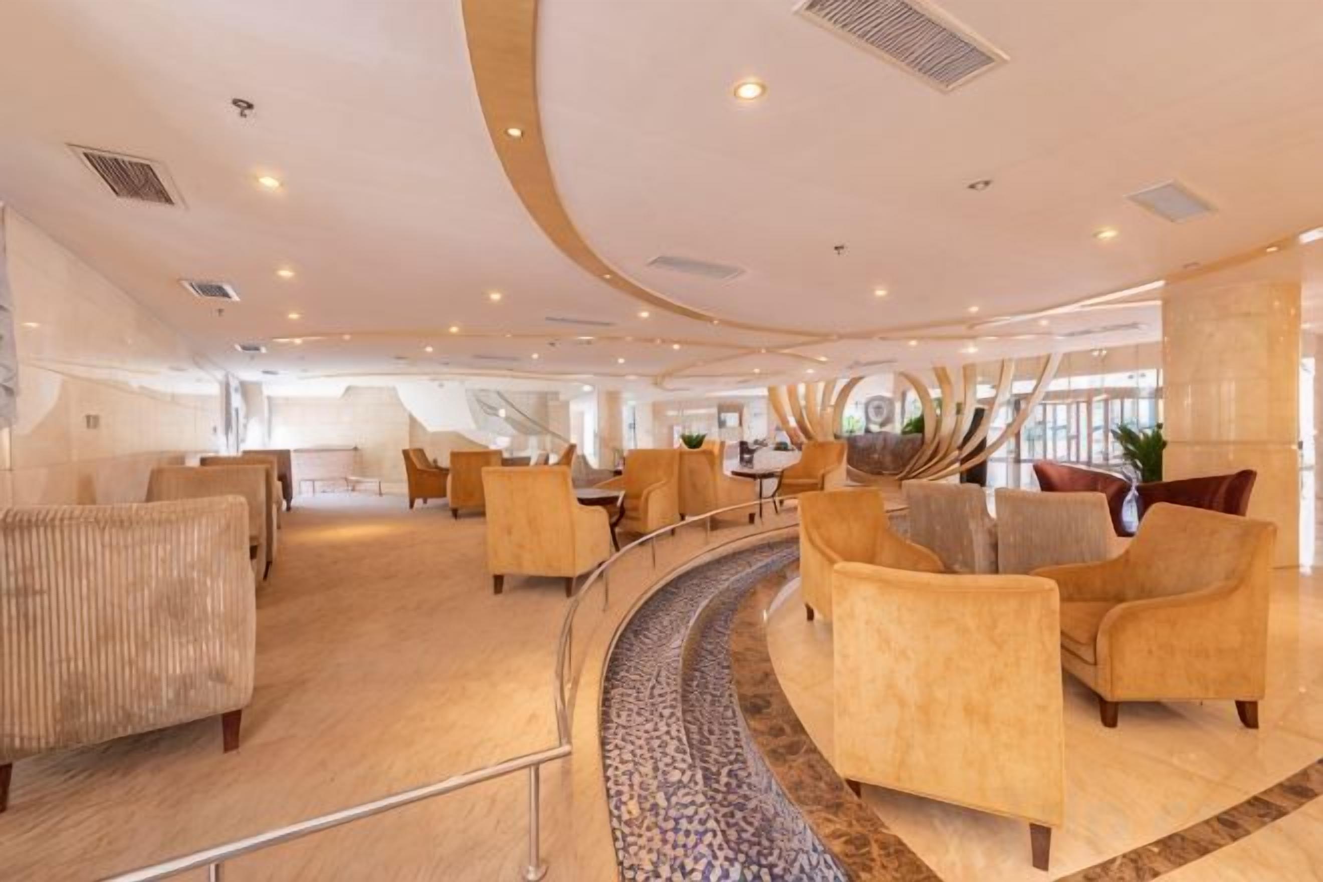 Een ruime, moderne lounge met gebogen zitplaatsen en een decoratief middelpunt.