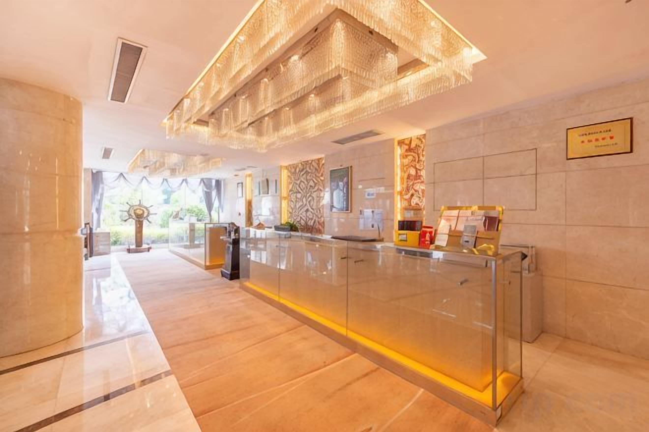 A reception area with a glass partition, a reception desk, and a chandelier.