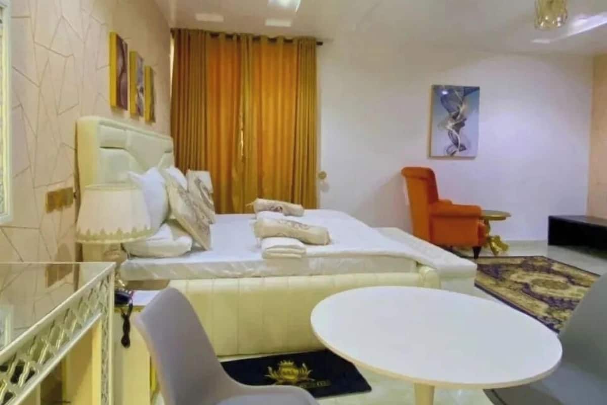 Una habitación de hotel moderna con una cama, una mesa de comedor y dos sillas.