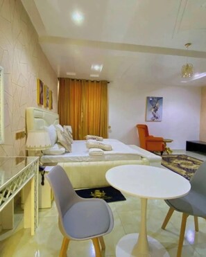 A modern hotel room with a bed, a dining table, and two chairs. - Silicon Valley Resort (Enugu)