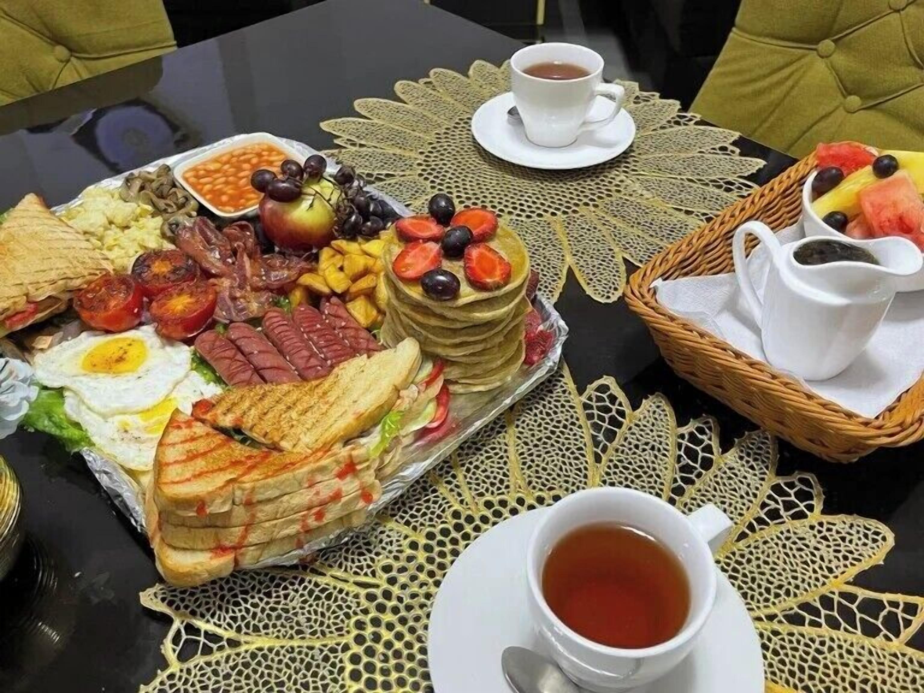A breakfast buffet with various foods and a cup of tea on a table.