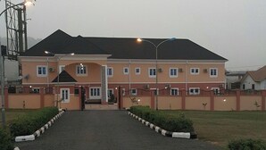 A large, multi-story building with a symmetrical facade, a central entrance, and a paved driveway leading to the entrance. - Silicon Valley Resort (Enugu)