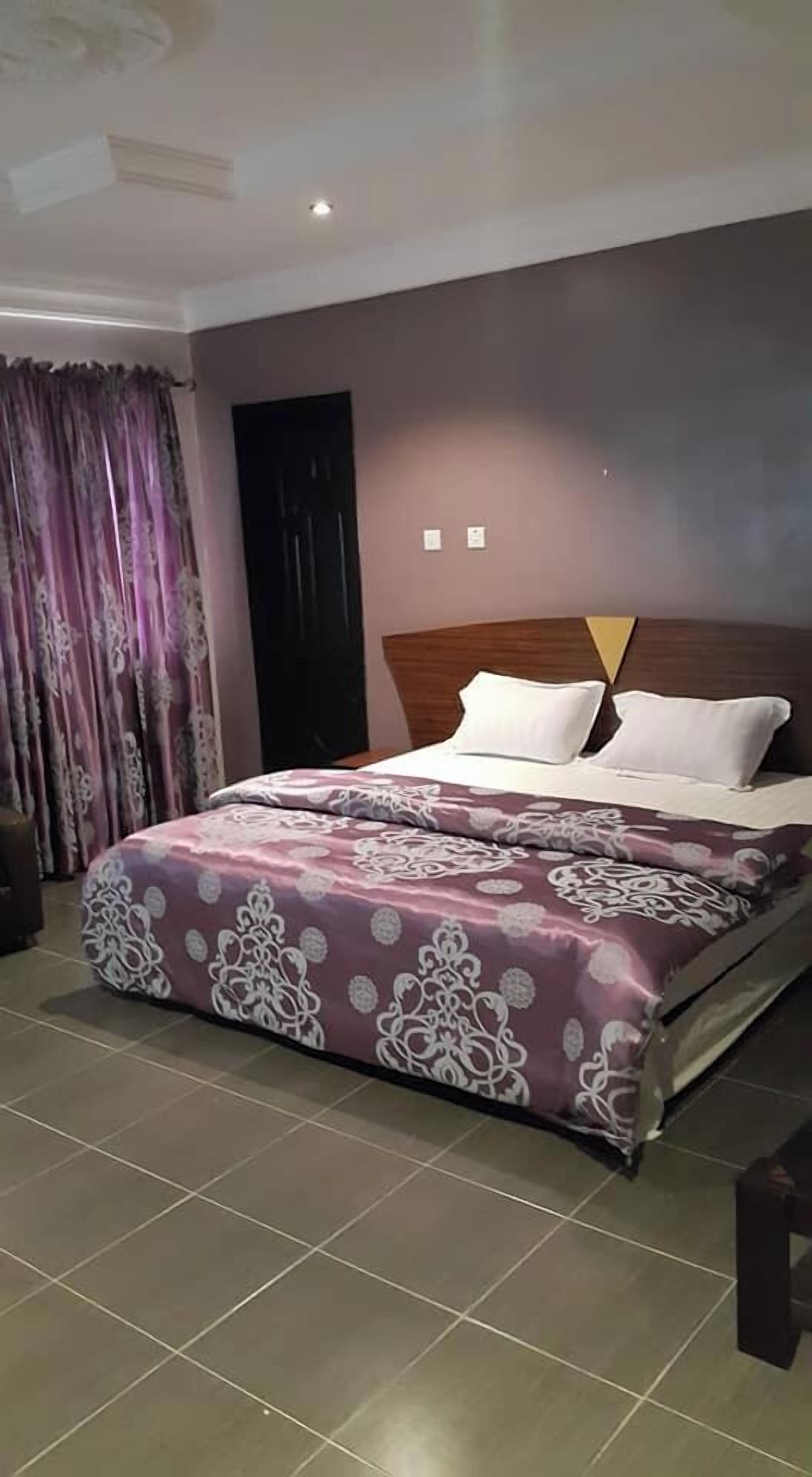 A bedroom with a bed, curtains, and a door.