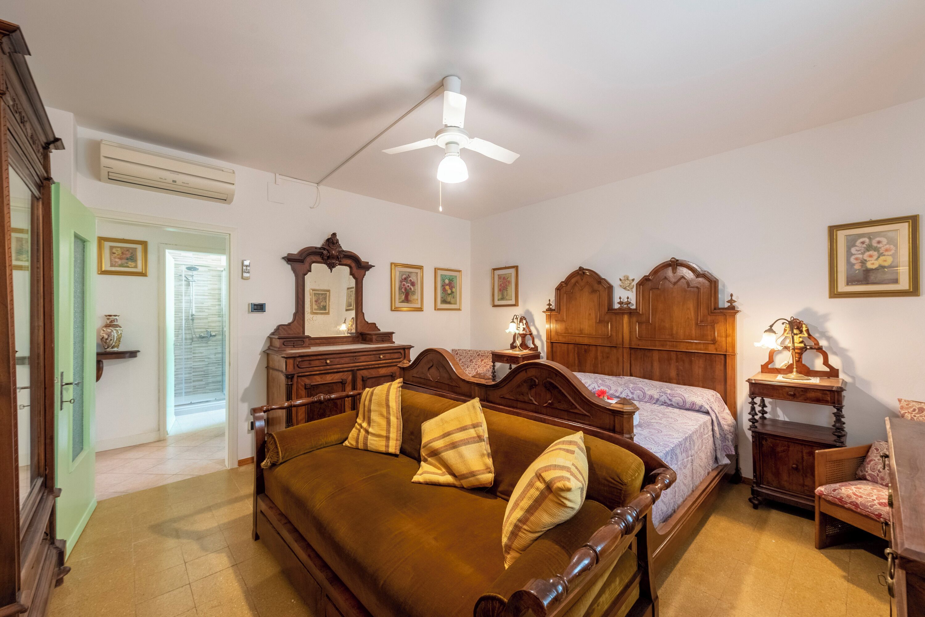 A bedroom with a bed, a wooden dresser, a nightstand, a chair, and a ceiling fan.