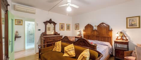 A bedroom with a bed, a wooden dresser, a nightstand, a chair, and a ceiling fan.
