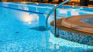 A swimming pool with a tiled edge and a hot tub area.