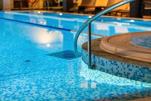 Une piscine avec un bord carrelé et un espace dédié à un jacuzzi.