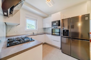 Una cocina moderna con estufa a gas, microondas, horno y refrigerador de acero inoxidable.
