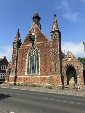 A historic church with a large arched window, a clock, and two bell towers. - Pine Cottage Retreat in Suffolk (Eye)
