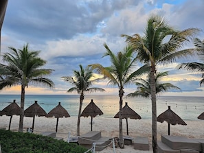 A beach with palm trees and thatched umbrellas, a clear view of the ocean, and a sandy beach area. - Chemuyil Jungle Villa - 2BR and Plunge Pool (Ciudad Chemuyil)