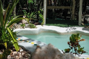 A pool with a white edge, surrounded by rocks and plants. - Chemuyil Jungle Villa - 2BR and Plunge Pool (Ciudad Chemuyil)