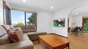 A modern living room with a sectional sofa, a wooden coffee table, and a dining area with chairs and a table.