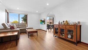 A spacious living room with a sofa, coffee table, and wooden cabinet.