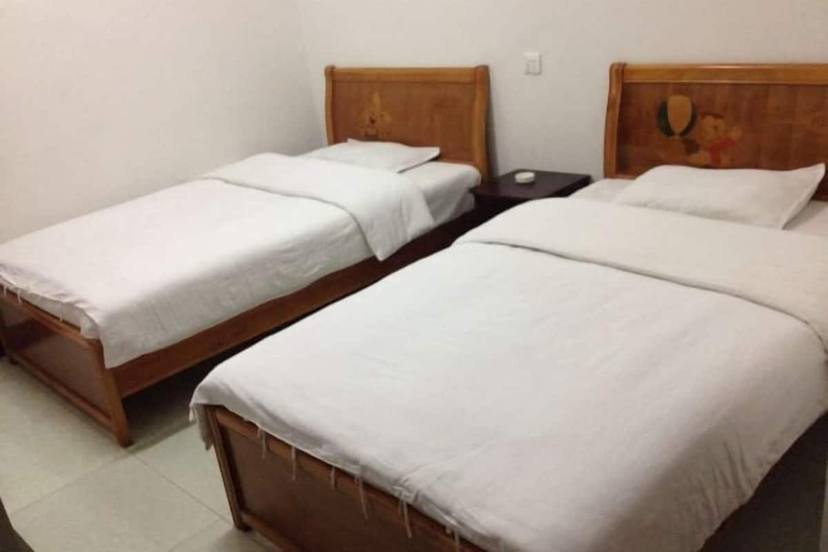 Dos camas individuales con cabeceros de madera, una mesita de noche y un interruptor de luz en la pared.