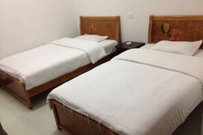 Two single beds with wooden headboards, a nightstand, and a wall-mounted light switch. - Yugancheng Xianglou Hotel (Yugan)