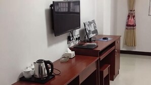 Una habitación de hotel con escritorio, televisión, cafetera y un marco de fotos.