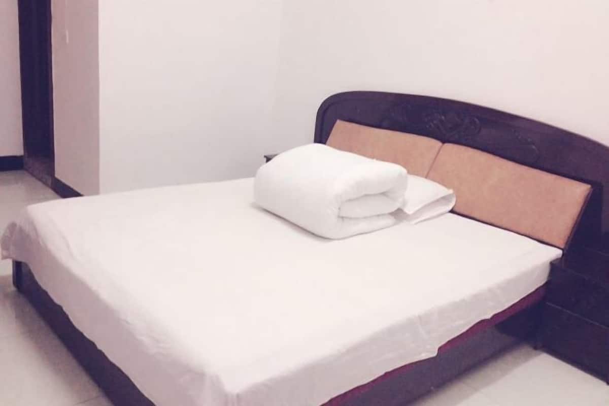 Una cama bien hecha con sábanas blancas y una toalla doblada sobre el cabecero.