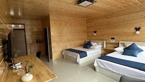 A wooden cabin-style room with two beds, a small table, and a wall-mounted light fixture. - Taoran Farmhouse (Mohe)