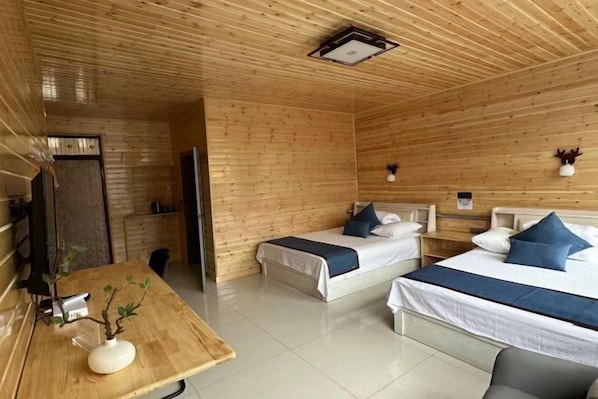 Une pièce en bois avec deux lits, une table sur laquelle se trouve un vase, et un luminaire au plafond.