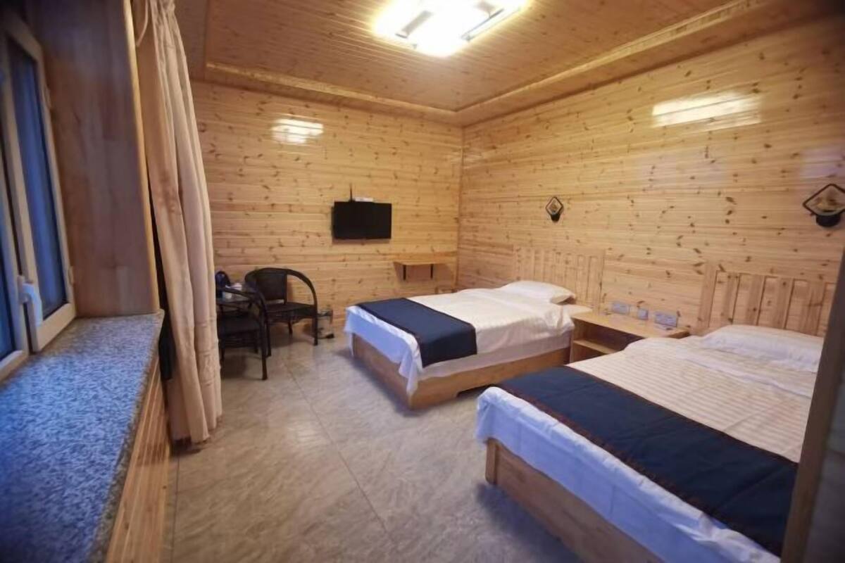 Una habitación tipo cabaña de madera con dos camas, un escritorio, una silla y un televisor.