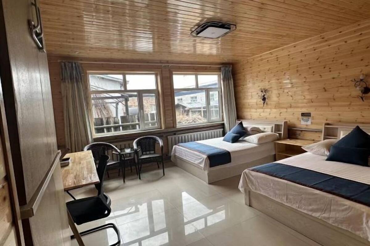 Una habitación con dos camas, un escritorio, una silla y una ventana.