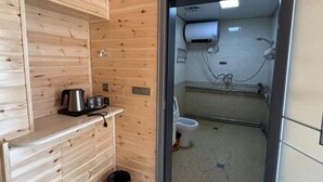 A wooden cabin interior with a kitchenette area, a toilet, and a shower. - Taoran Farmhouse (Mohe)